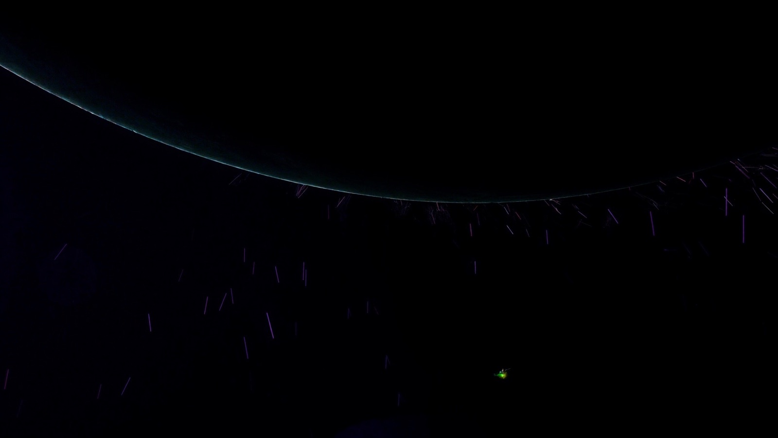 Earth's limb at night ringed by faint debris streaks, a single satellite firing a chartreuse de-orbit burn
